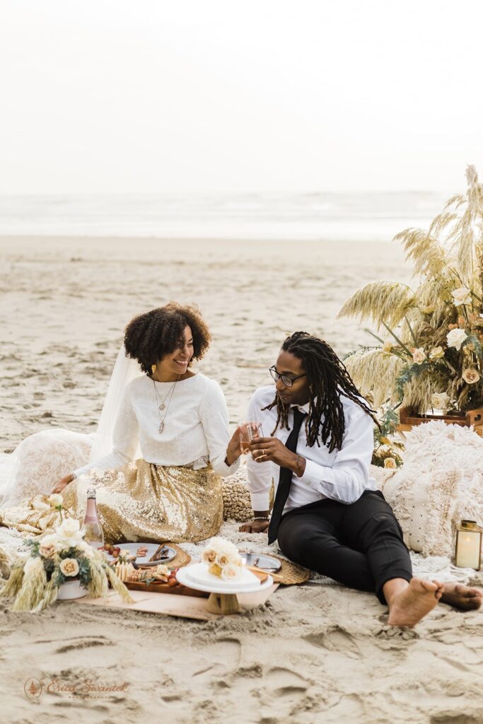 A couple shares a beach picnic during their boho elopement in Oregon.