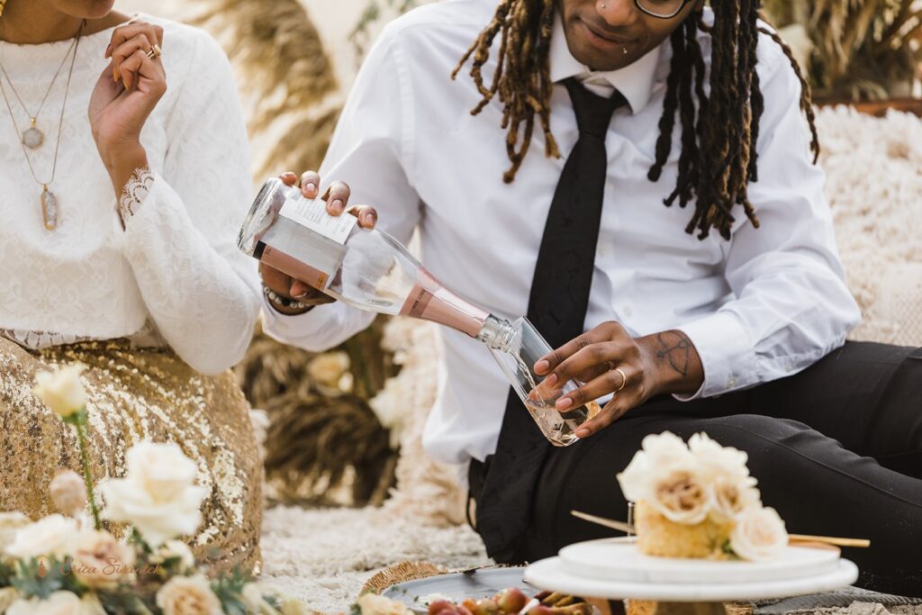 A man pours a glass of rose during an boho picnic at Proposal Rock.