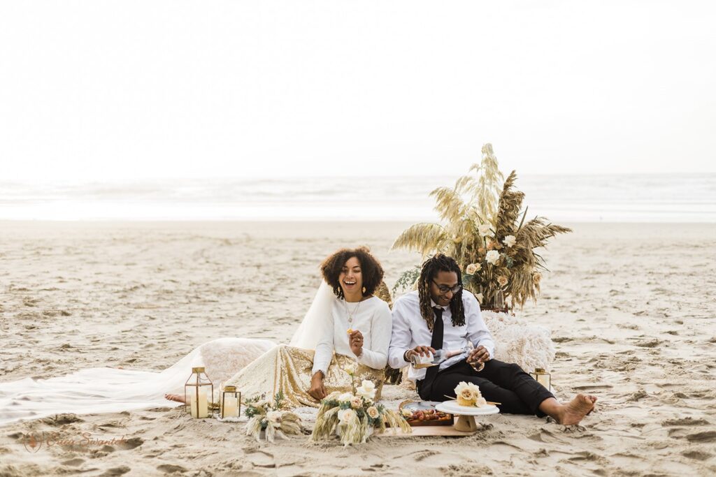 A couple shares smiles and laughter during a boho picnic wedding along the Oregon Coast. 