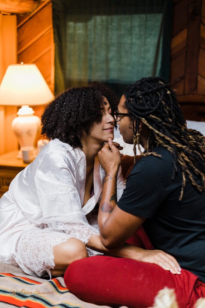 A couple goes in for a kiss while sitting in bed at their Oregon Airbnb.
