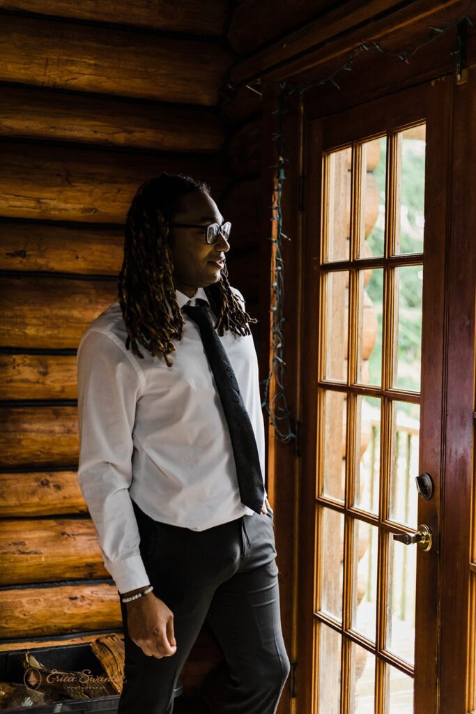 A groom poses inside an Oregon Airbnb in wedding attire. 
