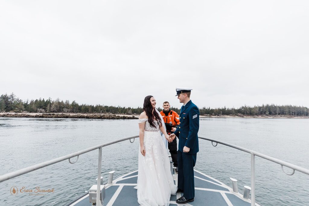 A couple holds hands after their boat vow ceremony on a bay along the Oregon Coast.