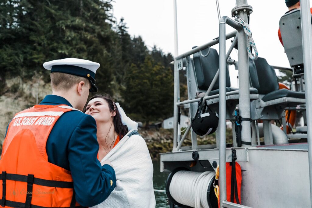 A couple embraces on a boat on Winchester Bay during their Coast Guard elopement.