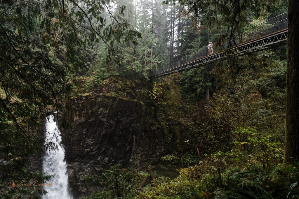 A couple stands on a suspension bridge that looks down onto Drift Creek Falls in Siuslaw National Forest. 