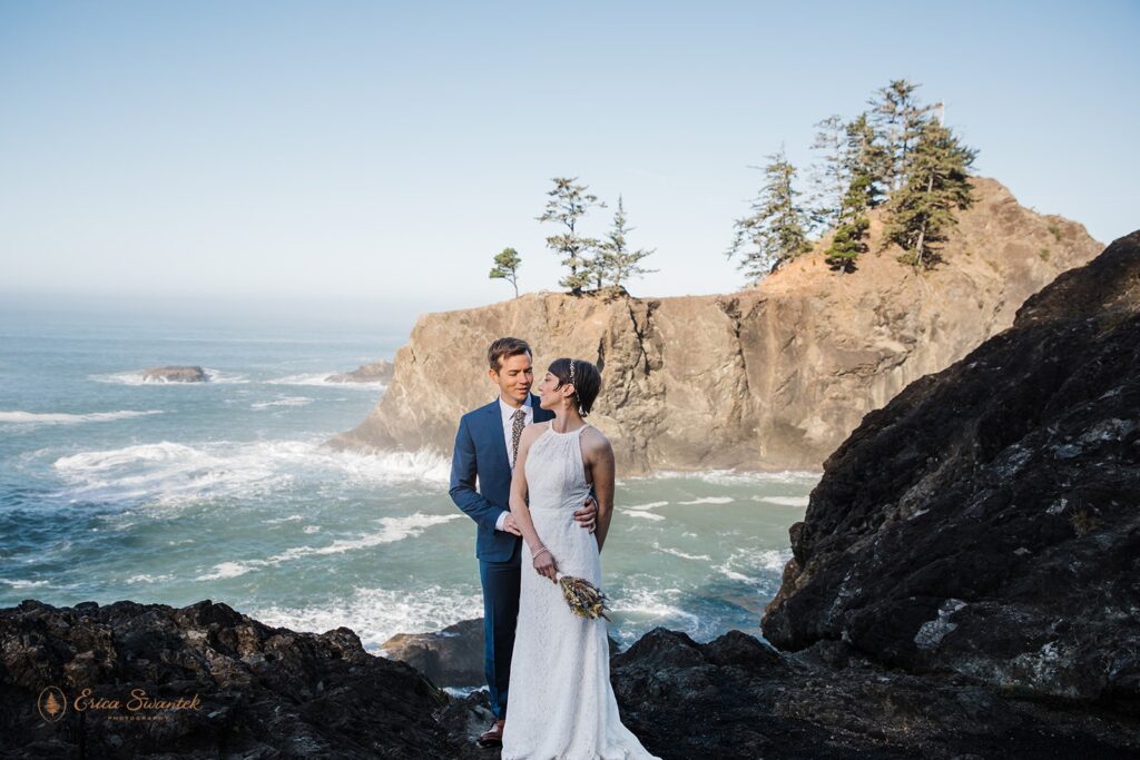 A couple poses along a cliff's edge overlooking the Pacific Ocean in Samuel H. Boardman State Park.