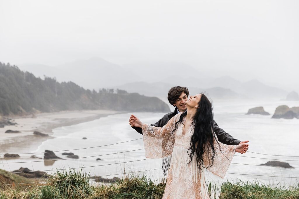A newylwed couple stands at an overlook in Ecola State Park.