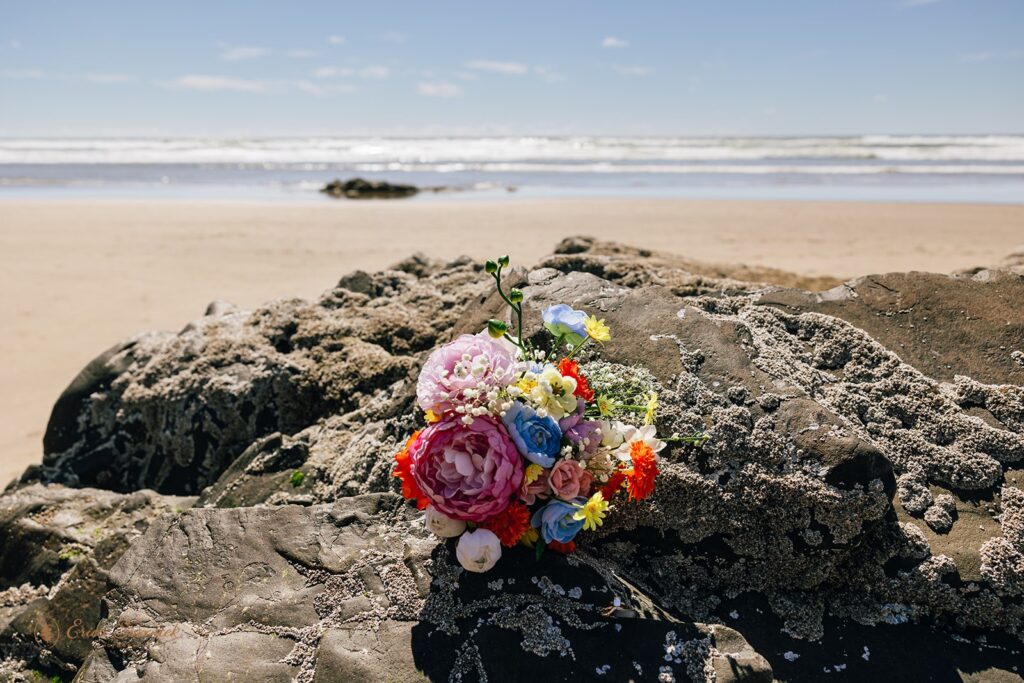 colorful elopement bouquet laid on a rock during an oregon coast elopement