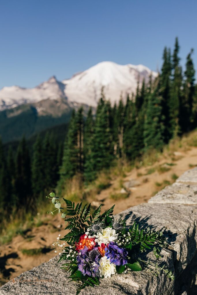 A colorful bridal bouquet rests on a stone ledge overlook in Mt. Rainier National Park. 