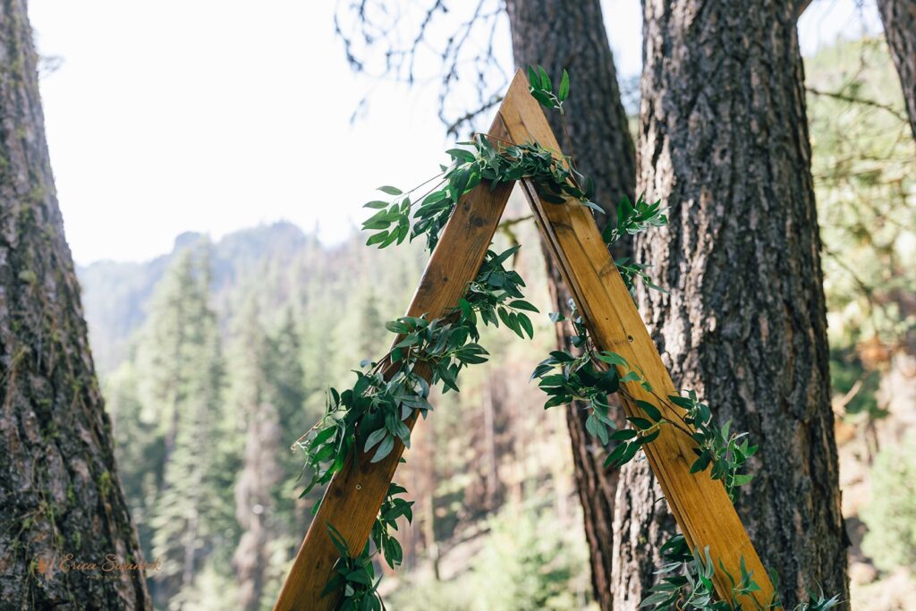 An a-frame wooden arch decorated with greenery. 