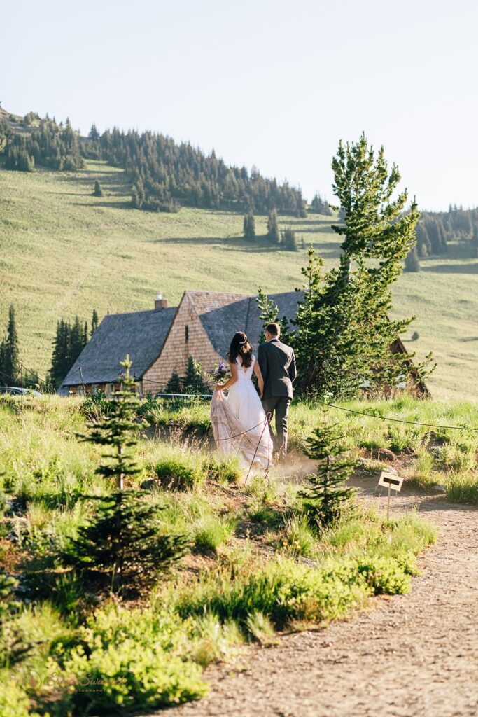 A hiking elopement couple holds hands while walking to the parking lot at Sunrise Visitors Center in Mt. Rainier National Park. 