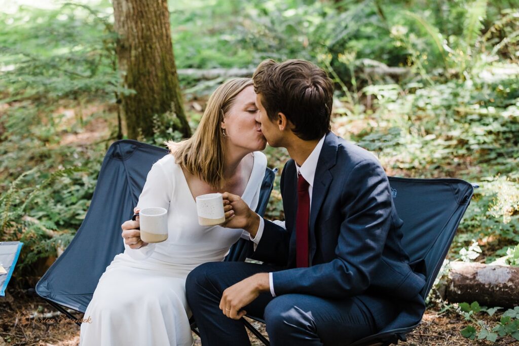 A couple shares a kissing while having celebratory drinks during their picnic elopement at Mt. Rainier. 