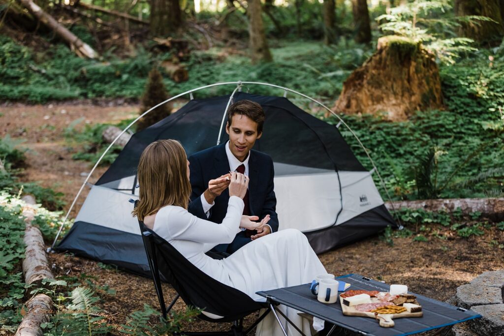 A couple shares small bites at a campsite near Mt. Rainier during their camping elopement in Washington. 