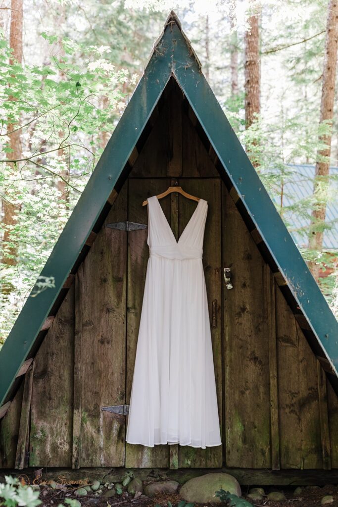 A wedding dress hangs from a cabin in the woods near Mt. Rainier National Park
