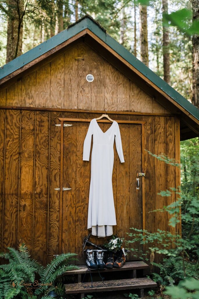 A long sleeve white wedding dress hands from a cabin door just above Scarpa boots, mountaineering axes and a bridal bouquet. 