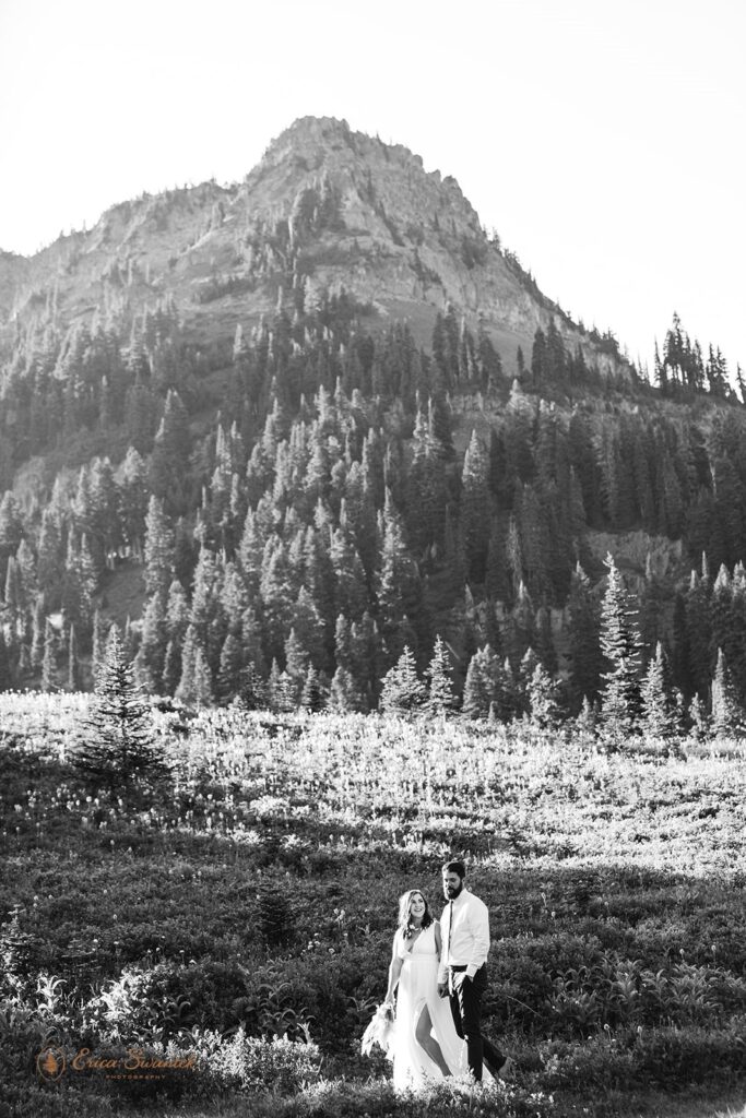 A lakeside elopement couple holds hands while walking along a lake trail in Mt. Rainier National Park. 