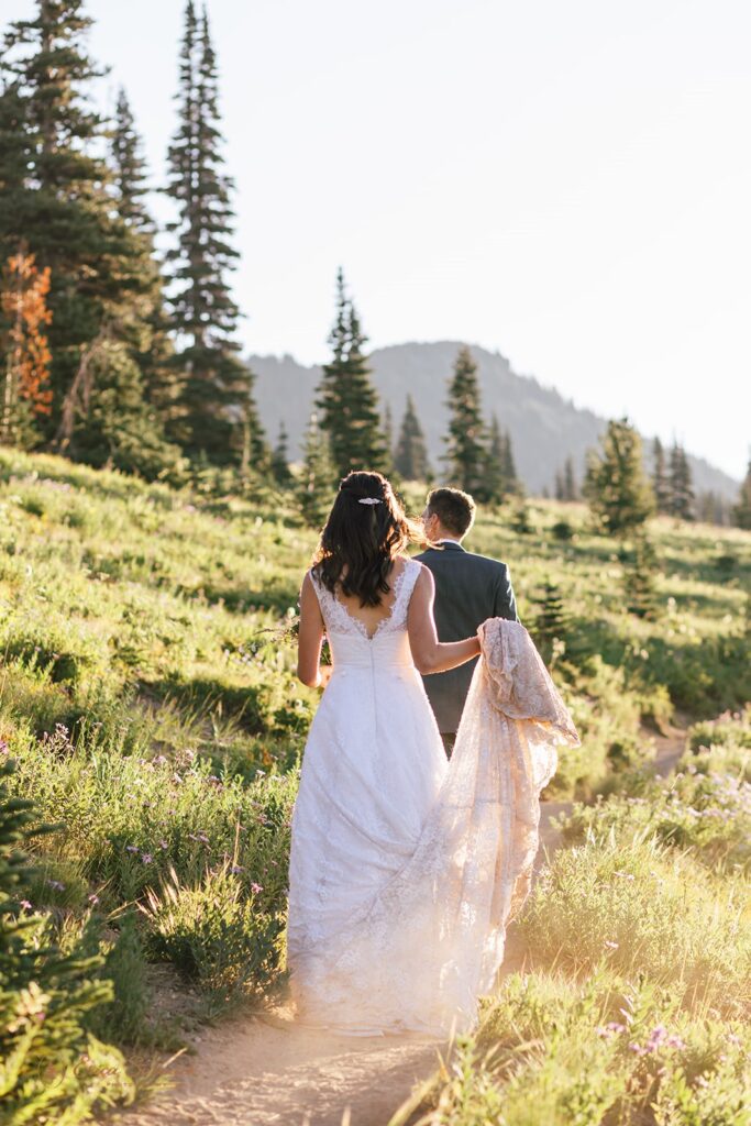 A hiking elopement couple walks along a wildflower trail in Mt. Rainier National Park.