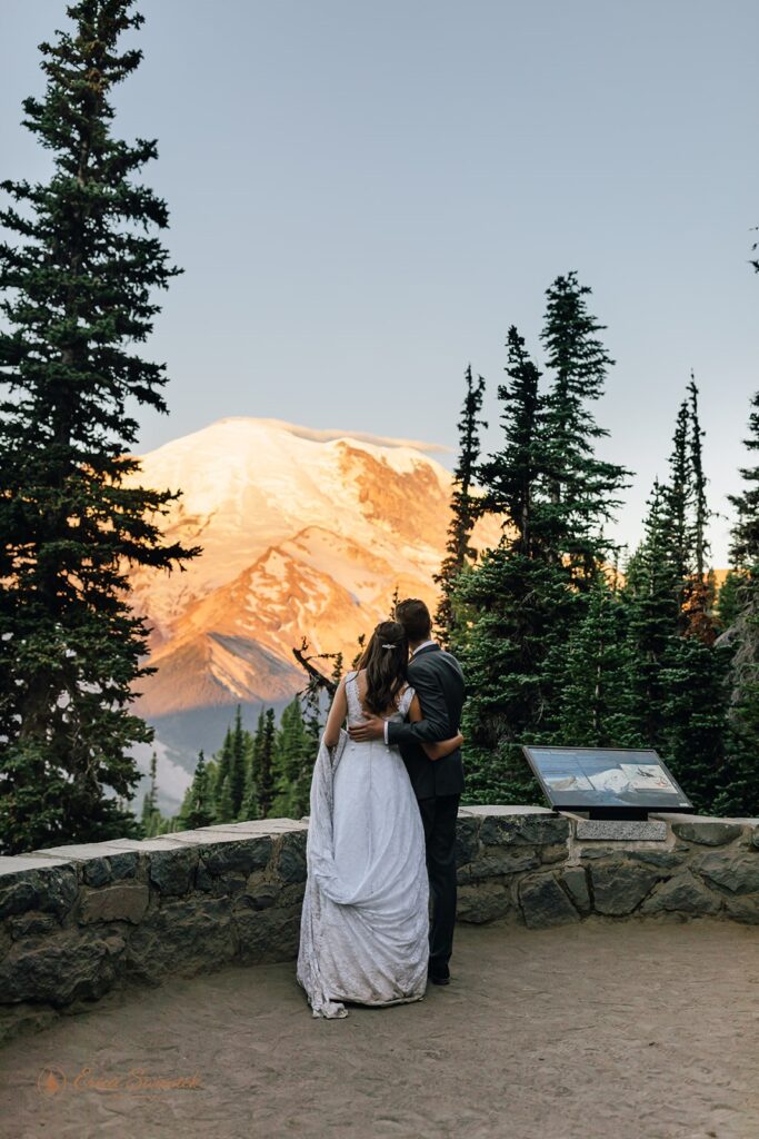 A couple embraces while admiring Mt. Rainier at Sunrise on an overlook along Silver Forest Trail. 