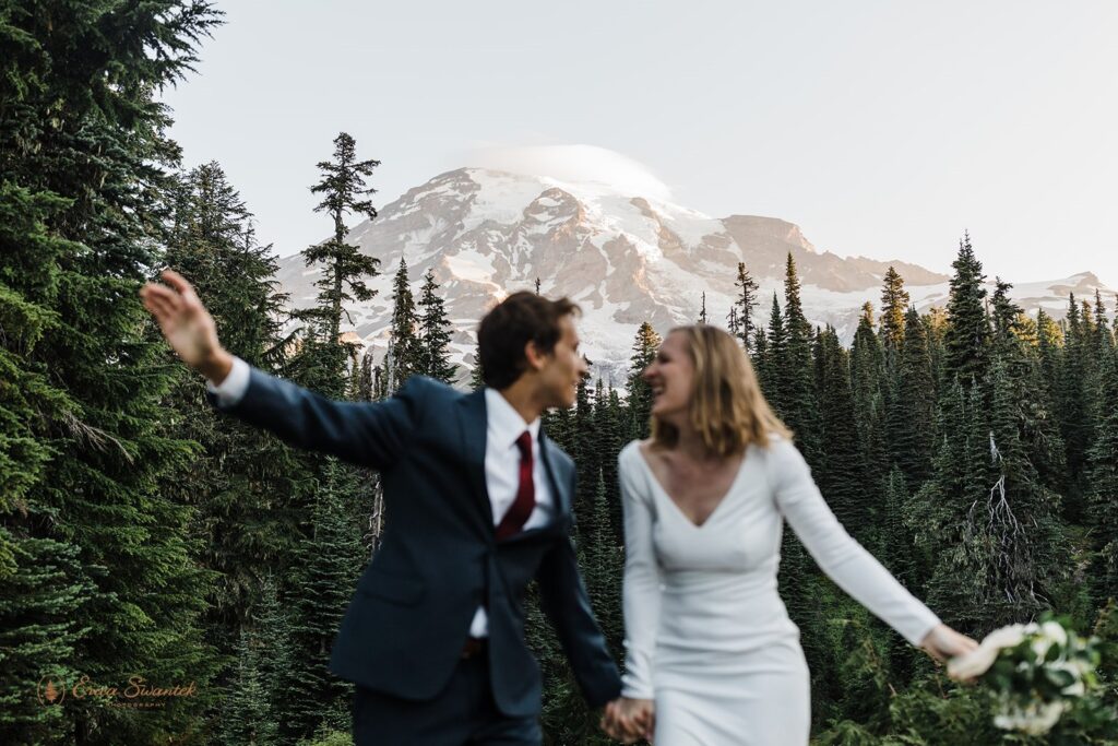 A blurry, celebratory photo of a Mt. Rainier elopement couple walking along a hiking trail. 
