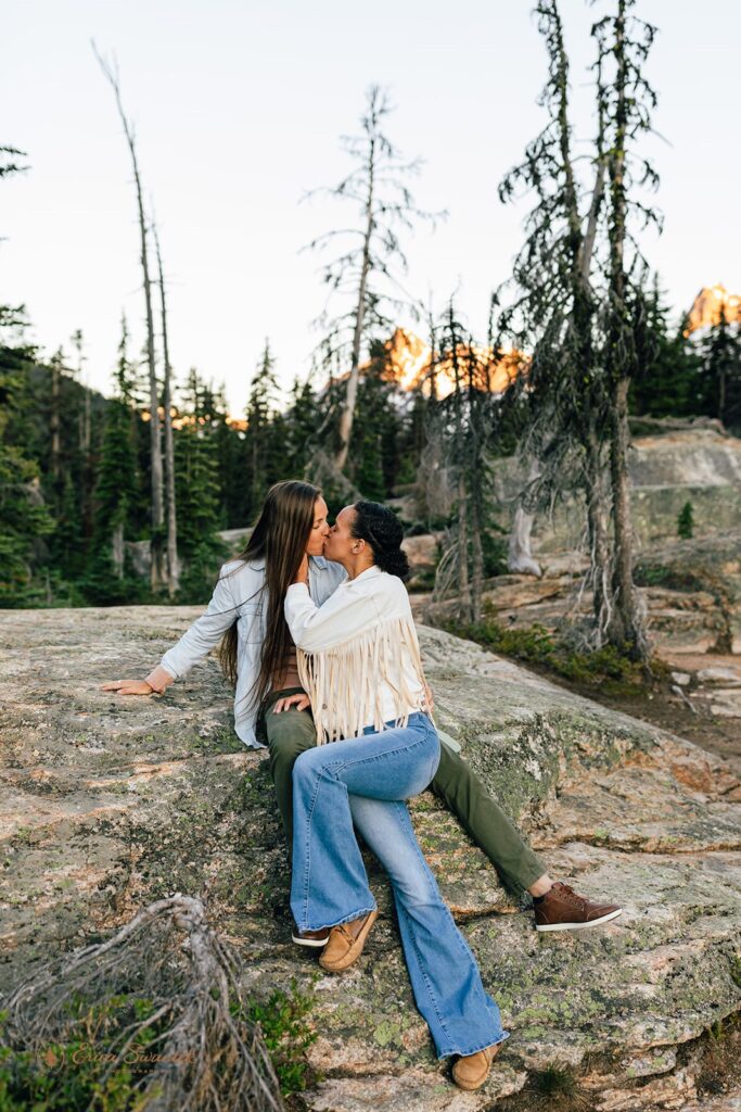 A couple kisses as they sit on a large boulder in the North Cascades during their Washington couples session. 