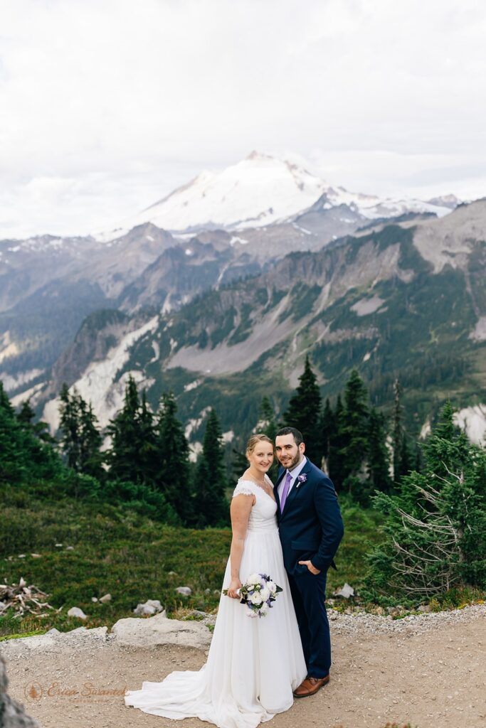 A North Cascades elopement couple poses for a wedding portrait with Mr. Baker in the background at Sunrise. 