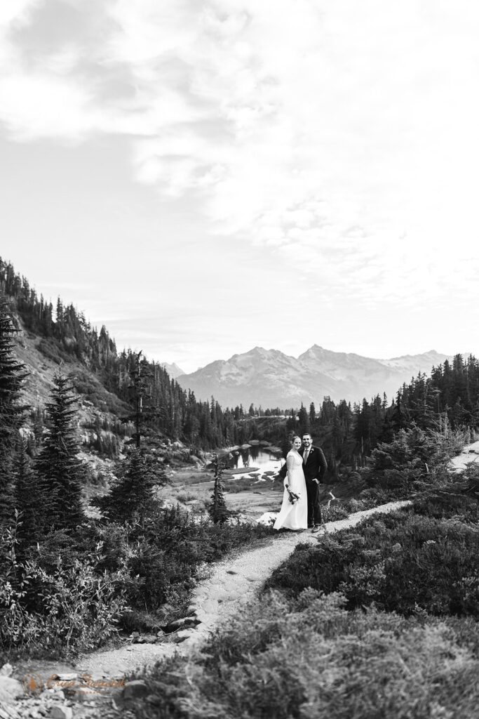 A North Cascades elopement couple stands on a bridge in a path at Reflection Lakes for wedding portraits. 
