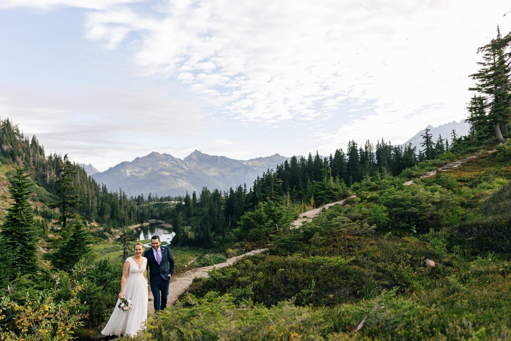 A couple walks along a Washington hiking trail at Reflection Lakes during their adventure elopement. 
