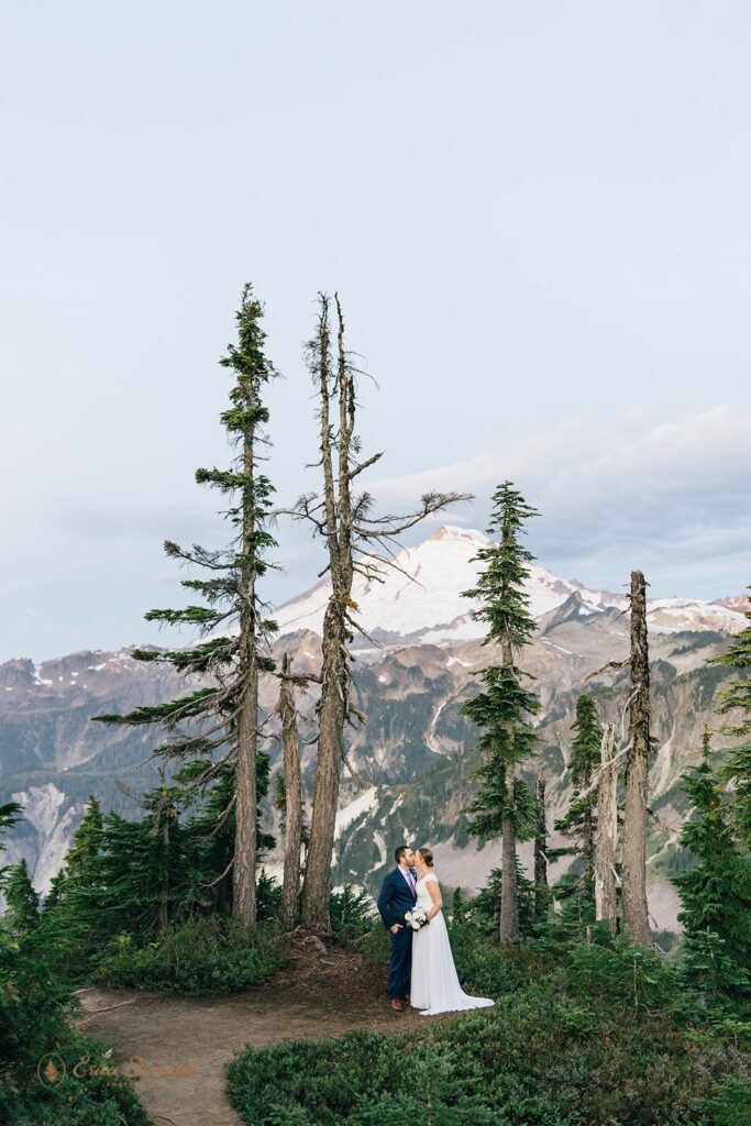 A Washington elopement couple stands on Artist Ridge Trail while kissing during their outdoor ceremony. 