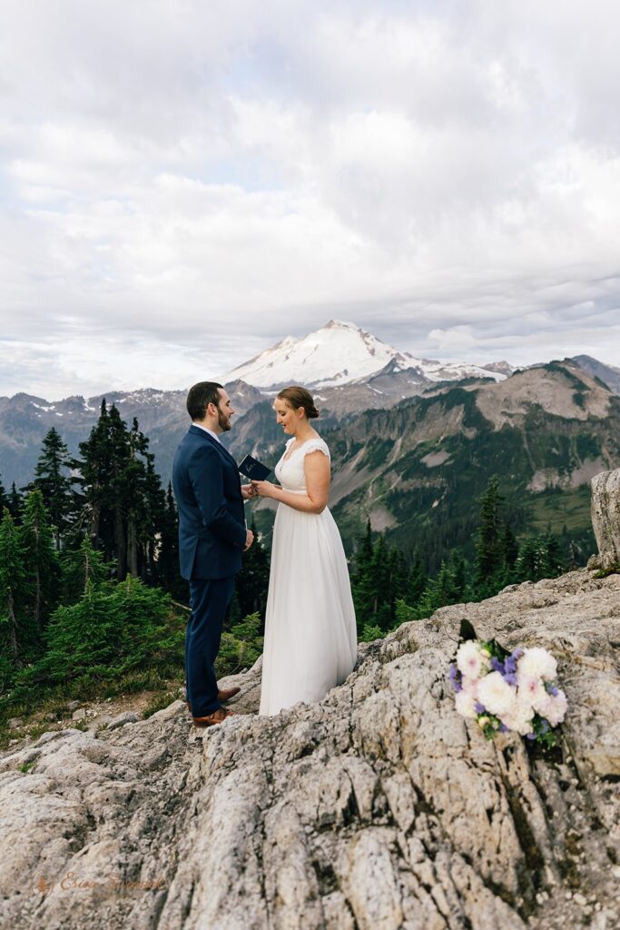 A North Cascades elopement couple recites vows to one another with snowy Mt. Baker in the distance. 