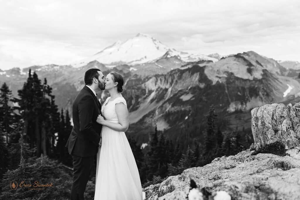 A couple in formal wedding attire kisses during their North Cascades elopement ceremony near Mt. Baker. 