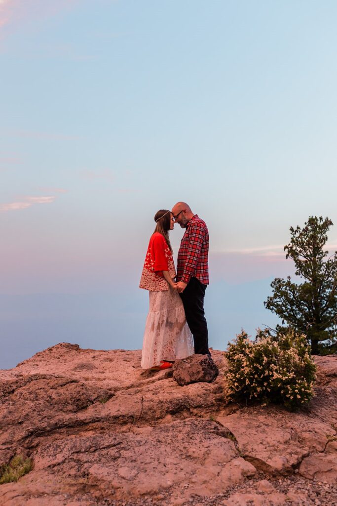 An Oregon elopement couple embraces during Sunset on a cliffside in Crater Lake National Park. 