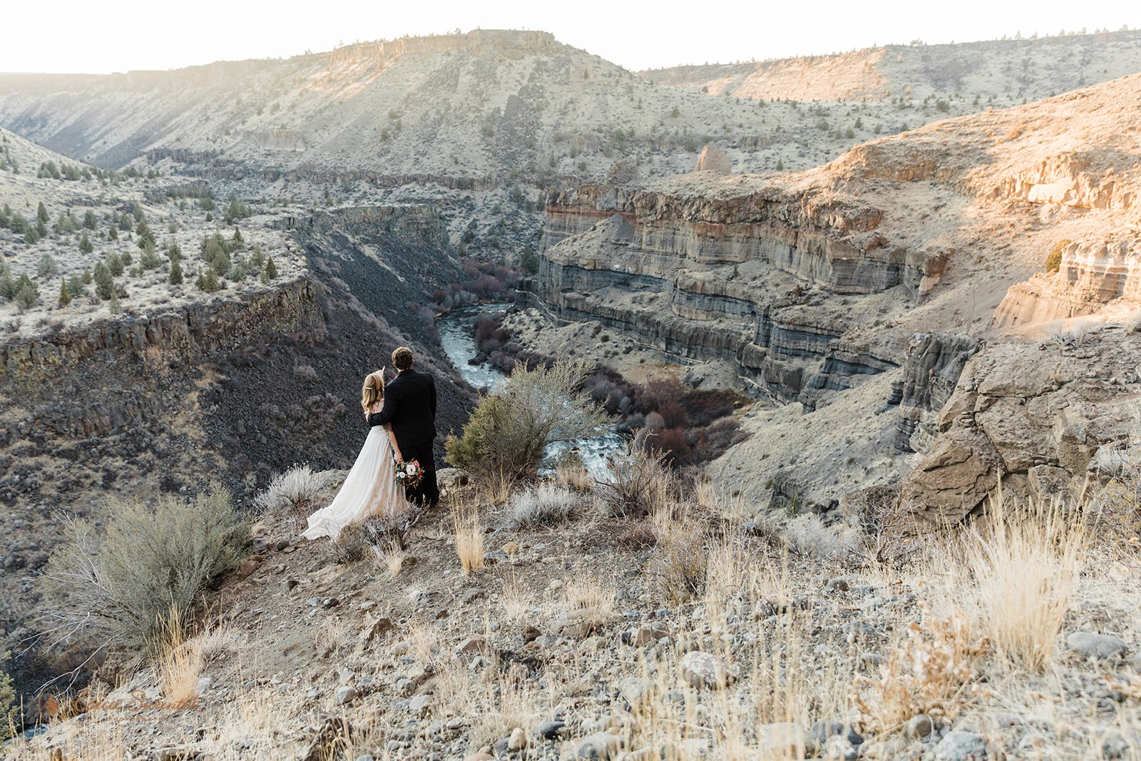 A Bend, Oregon, elopement couple stands on a cliff's edge overlooking Desert Canyon.