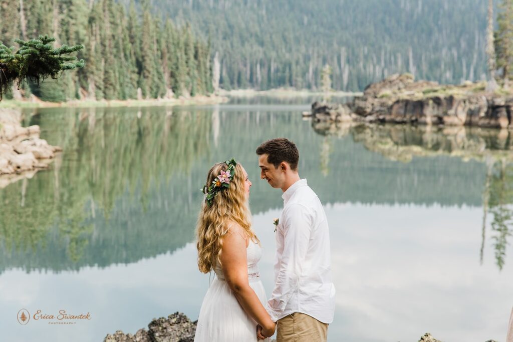 A hiking elopement couple holds hands during a vow ceremony at Sparks Lake. 