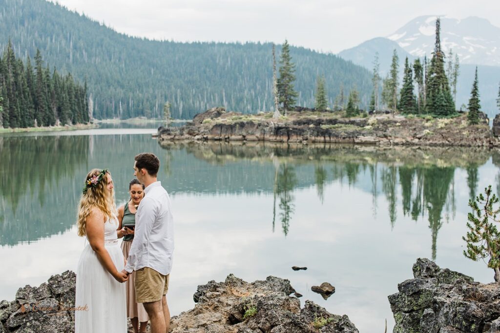 A adventure elopement couple holds hands during a vow ceremony at Sparks Lake. 