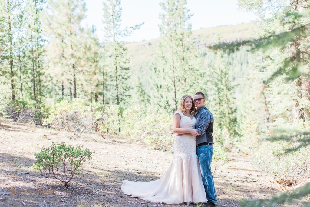 A bride and groom embrace for a forest wedding portrait at Skyliner's Lodge. 
