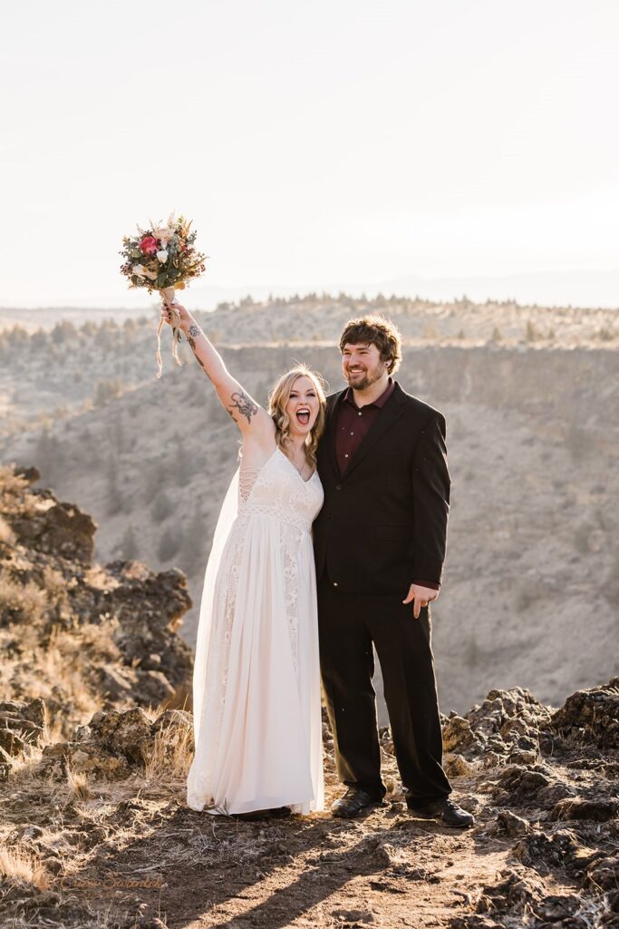A bride wearing a floor length wedding dress holds a bridal bouquet while celebrating her Bend, Oregon, elopement with her groom. 