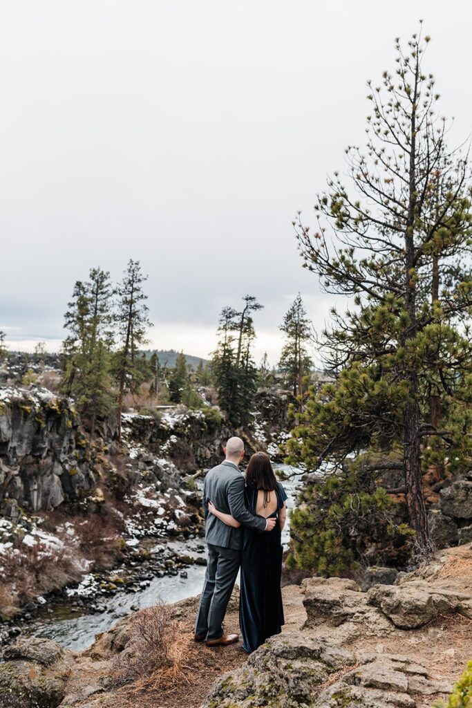 A couple admires Dillion Falls before their outdoor elopement in Bend, Oregon. 