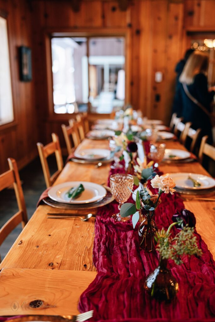 A burgundy tablescape on a wooden table.