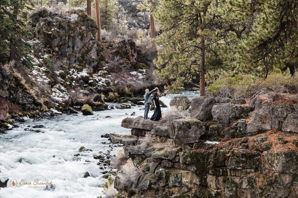 A bride and groom dance on a cliff overhang near Dillon Falls during their outdoor elopement in Oregon. 