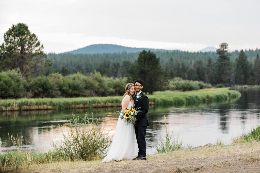 A couple dressed in formal wedding attire embrace near Sunriver during their intimate wedding portraits in Oregon. 