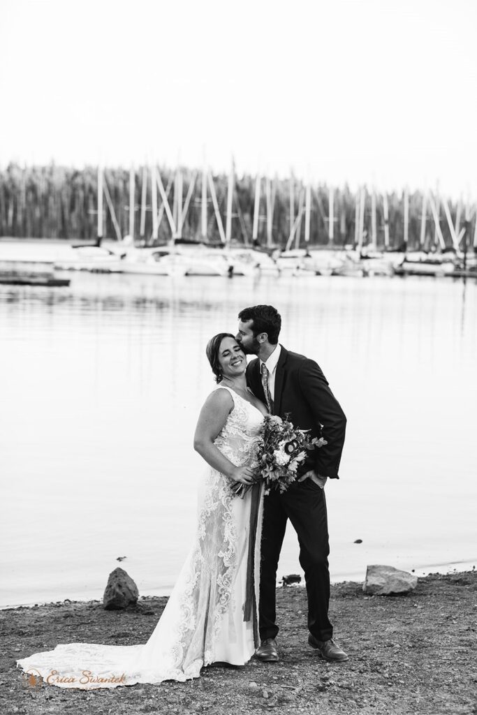 An Oregon intimate wedding couple pose for a portrait near sailboats at Elk Lake. 