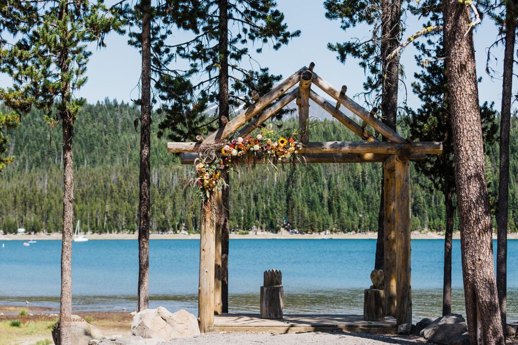 A wooden ceremony arch decorated with a sunflower arrangement at Elk Lake Resort's ceremony site. 