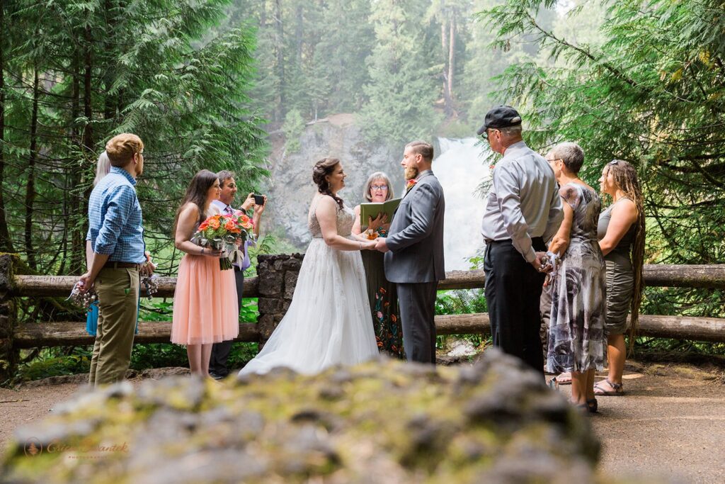 An Oregon officiant guides a vow ceremony of a groom and bride eloping at Sahalie Falls. 