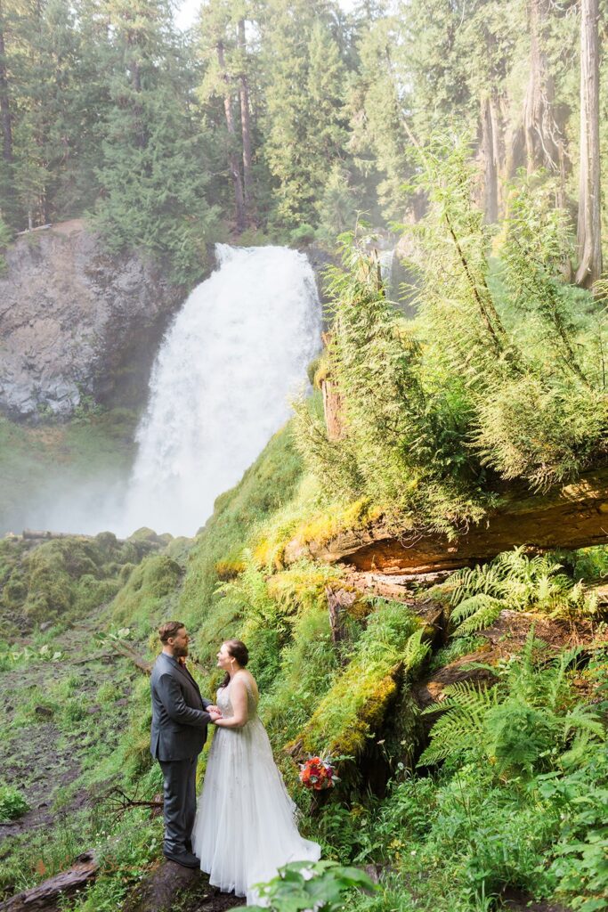 A waterfall elopement couple stand near Sahalie Falls in Bend, Oregon. 