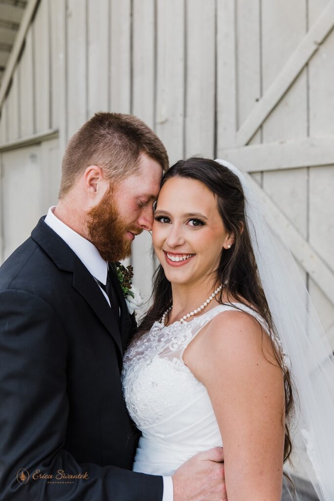 A groom rests his forehead on his bride's near a barn door during wedding portraits at Black Butte Ranch. 