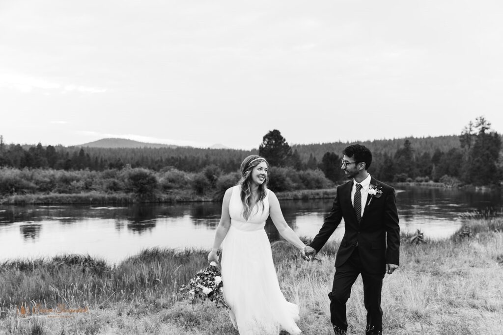 An Oregon wedding couple holds hands while walking along Sunriver near Bend, Oregon. 