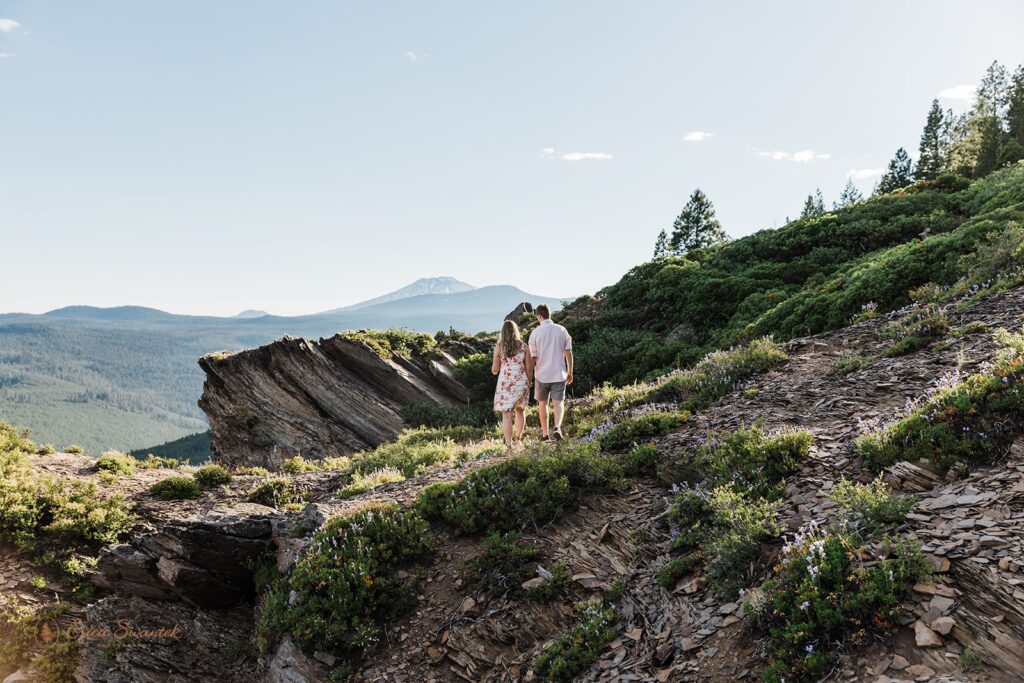 An Oregon elopement couple holds hands on an overlook while hiking during their Bend elopement. 