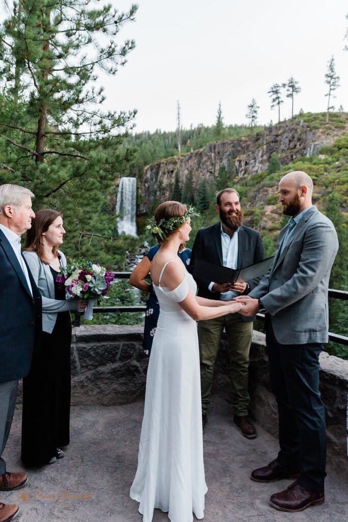 A hiking elopement couple dressed in formal wedding attire recite vows with an Oregon officiant during their Tumalo Falls ceremony. 