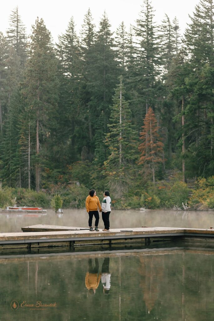 Two women hold hands on a pier at a lake in Sisters, Oregon. 