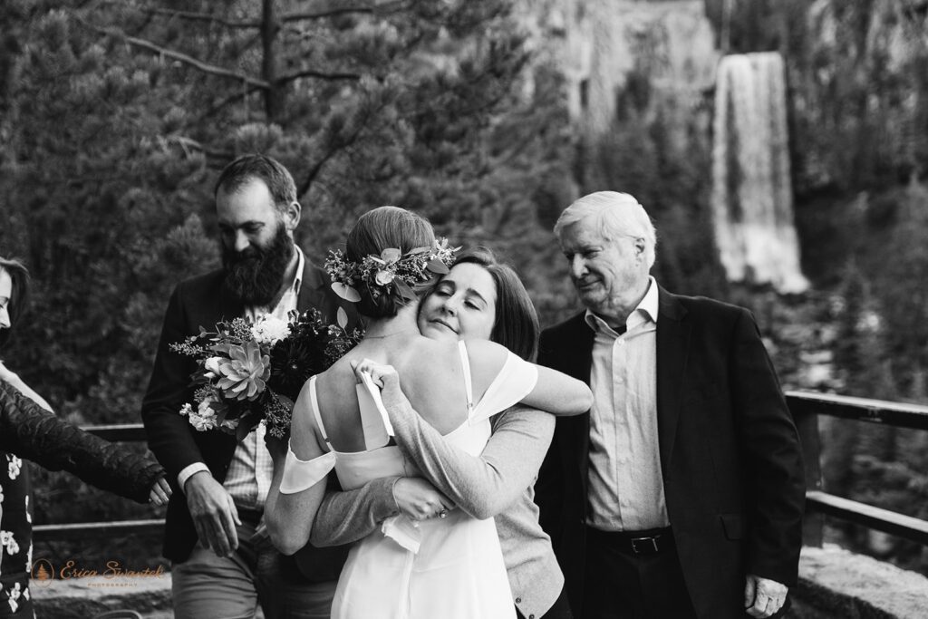A bride and family member embrace during a Tumalo Falls elopement ceremony in Oregon. 