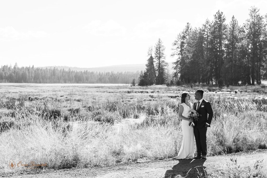 A couple dressed in formal wedding attire admires one another during their intimate Oregon wedding near Bend along the Deschutes River Trail.
